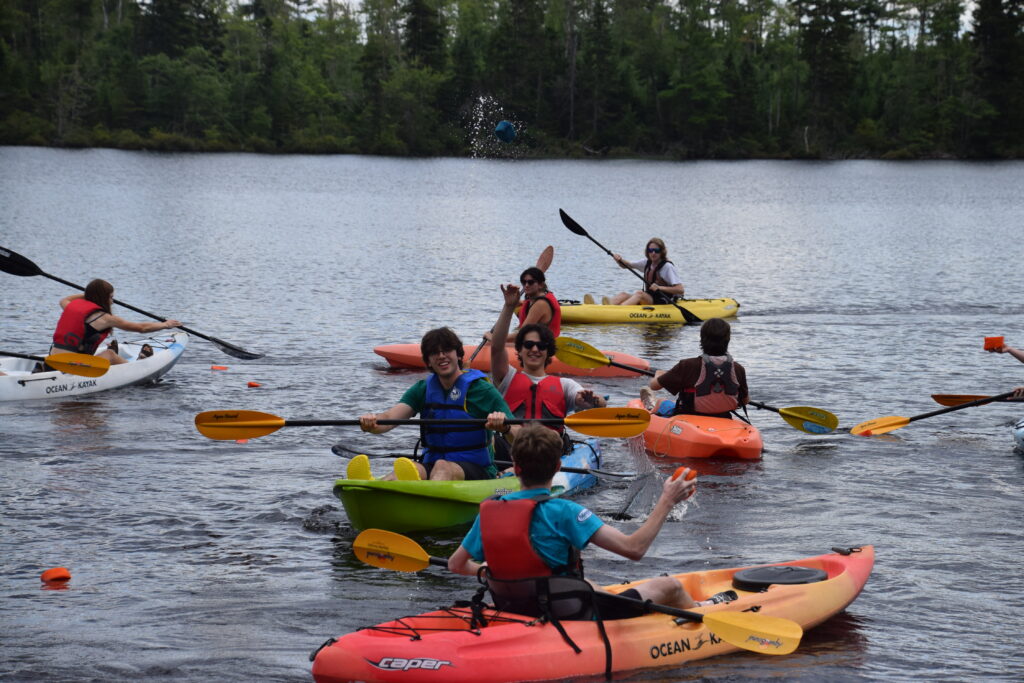 Youth in kayaks playing and paddling in the lake